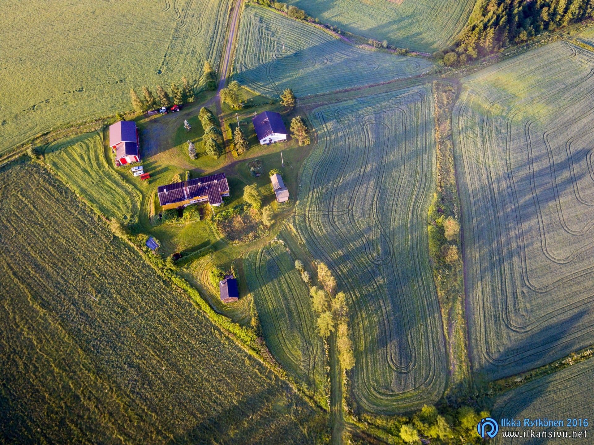Aerial view of farm buildings and long shadows across fields