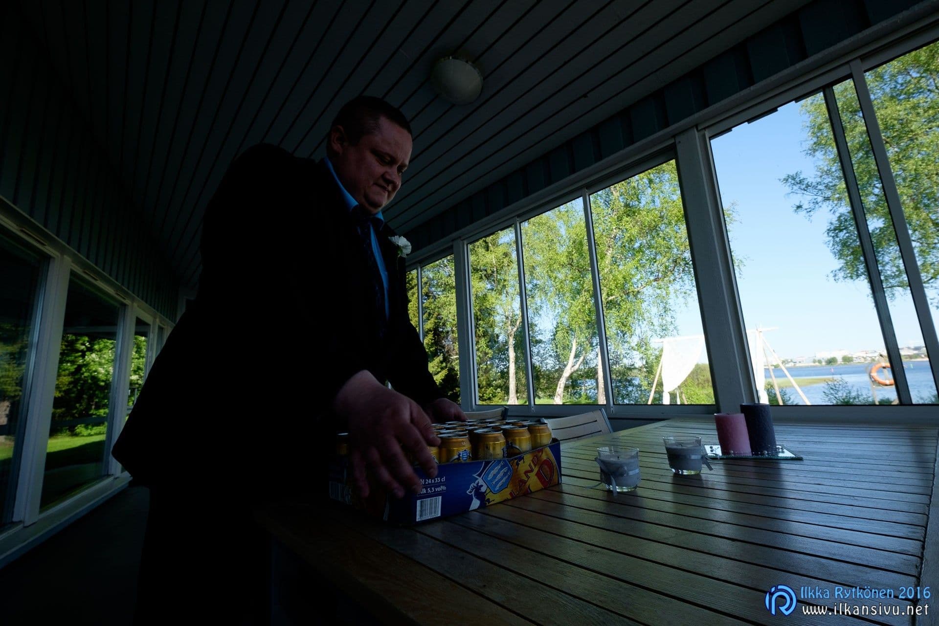 Mies lasiverannan pöydän ääressä, alkuperäisen kuvan sisätila jää tummaksi